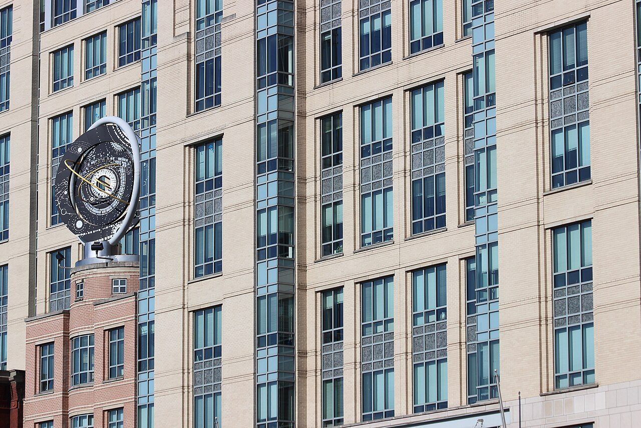 Fassade mit astronomischer Skulptur als ruhiges, ruhendes Gegenbild zur Bewegung der Daten